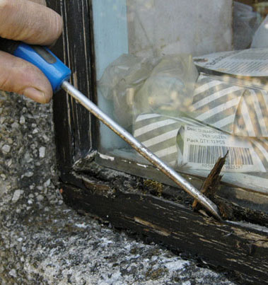 Testing for wood rot on a window using a screwdriver
